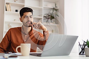 Arab man using laptop sitting at desk in office