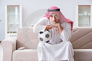 The arab man watching sport football at tv