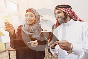 Arab man and woman working in offce. Coworkers are writing notes on glass board.