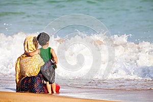 Arab mother and son hugging to the sea