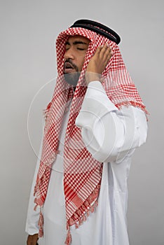 An Arab muezzin in a turban performs the call to prayer with one hand beside his ear