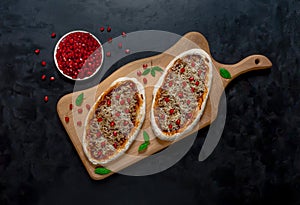 Arab pizza on a wooden stand. Scones with minced meat and pomegranate.