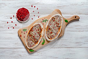 Arab pizza on a wooden stand. Scones with minced meat and pomegranate.