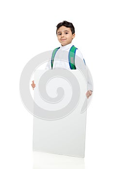 Arab school boy holding a big white board with both hands, wearing white traditional Saudi Thobe and sneakers, raising his hands photo
