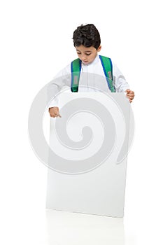 Arab school boy holding a big white board with both hands, wearing white traditional Saudi Thobe and sneakers, raising his hands photo