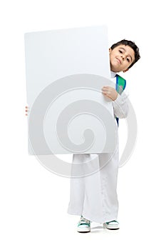 Arab school boy raising a big white board with both hands, wearing white traditional Saudi Thobe and sneakers, raising his hands photo