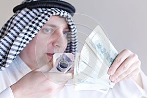 Arab sheikh from Arabia saudi, Emirates holds in hands drop of oil of Brent brand in crystal cube. Pack of hundred dollars bills. photo