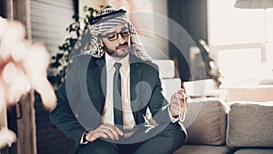 Arab sitting on couch and looking on chain