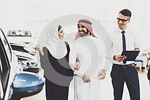 Arab smiles while looking at a big car.