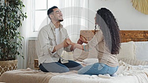 Arab spaniard man and woman, boyfriend and girlfriend, ethnic husband and wife, married couple sitting on bed in cozy