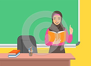 Arab teacher reads book near blackboard in class
