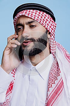 Arab in ghutra chatting on smartphone