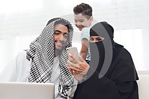 An arab woman in a burqa is looking at a mobile phone.