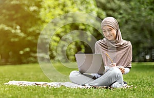 Arab woman freelancer working on laptop at park