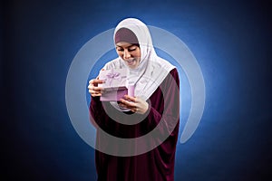 Arab woman in hijab is pleased with gift in box.
