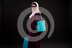 Arab woman in hijab and sunglasses holds paper