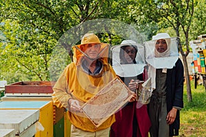 Arab woman investitors with an experienced senior beekeeper checking the quality and production of honey at a large bee