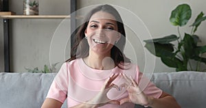 Arab woman makes with fingers heart smiling looking at camera