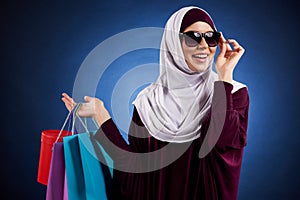 Arab woman in sunglasses holds paper colored bags