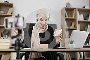 Arab woman using smart phone camera for creating content.