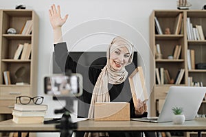 Arab woman using smart phone camera for creating content.