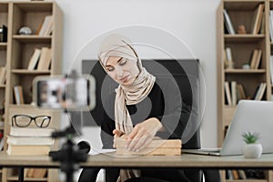 Arab woman using smart phone camera for creating content.