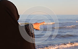 Arab woman with veil on her head pointing to a distant point in