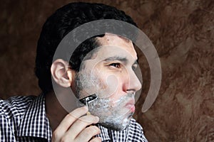 Arab young businessman shaving his beard with a razor