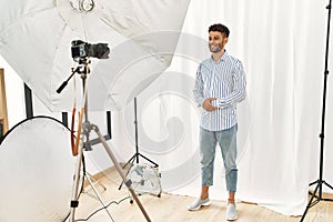Arab young man posing as model at photography studio with hands together and crossed fingers smiling relaxed and cheerful