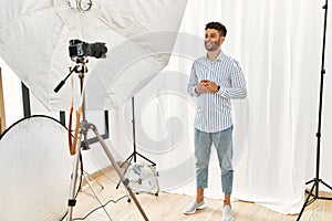 Arab young man posing as model at photography studio hands together and fingers crossed smiling relaxed and cheerful