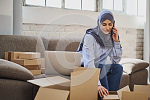 Arabian business woman having a phone call while packaging orders