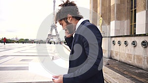 Arabian businessman arguing with partner by smartphone near Eiffel Tower.