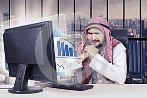 Arabian businessman and declining graph in office photo