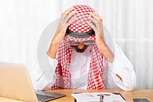 Arabian businessman feeling disappoint and suffer about his business in the office photo