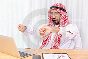 Arabian businessman feeling disappoint while talking with his business partner by video conference on notebook in his office