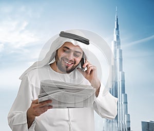 Arabian businessman reading news with burj khalifa