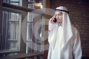 Arabian businessman talking on cell phone in company