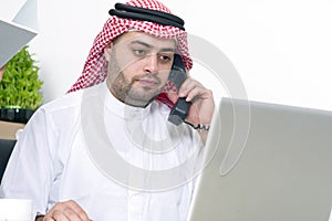 Arabian Businessman using Laptop and talking on phone