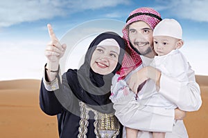 Arabian family looking at something on desert