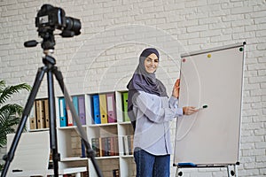 Arabian female coach making a video as she showing something on a whiteboard