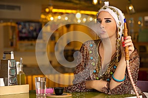 Arabian girl holding the hookah pipe in a coffee shop