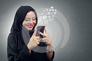 Arabian lady wearing hijab using her mobile with virtual apps icons