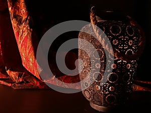 Arabian lantern near a red oriental fabric on a brown wooden background.Eid lamp or lantern for Ramadan and other Islamic Muslim