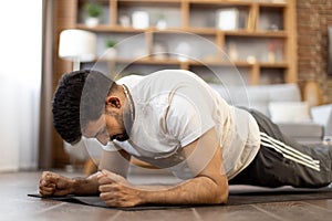 Arabian male athlete doing plank exercise at home