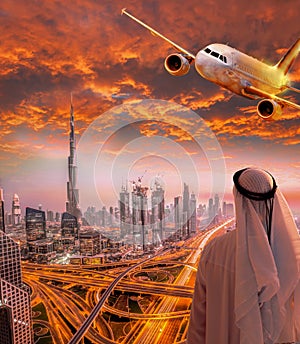 Arabian man with airplane flying over Dubai against colorful sunset in United Arab Emirates