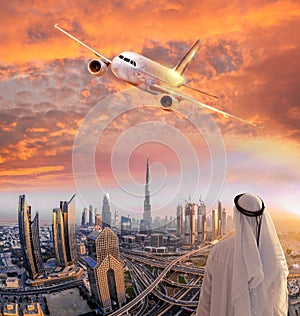 Arabian man with airplane flying over Dubai against colorful sunset in United Arab Emirates