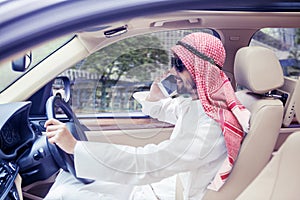 Arabian man driving a car while talking on phone