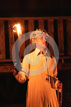 An Arabian man holding a fire torch in the front of a wooden house