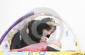 Arabian Mother feeding her baby girl on a play mat