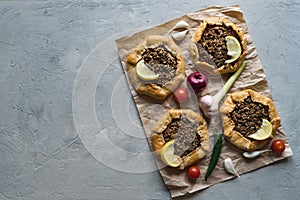 Arabian opened meat pies on gray background.